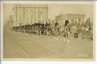 [Men marching in kilts and headdresses during a procession in an unknown location]