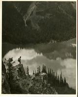 [View of a lake with a man standing on a cliff overlooking the lake]