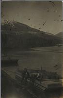 [Three men loading supplies onto a small wooden barge in T�te Jaune Cache, B.C.]