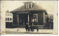 [Group portrait of four children in front of a dwelling in an unknown location]