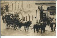 [Horse drawn carriage (Tally-Ho) full of people in front of a store on a street in an unknown location]