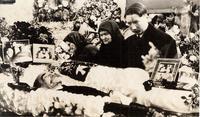 [Two Doukhobor women and a man next to Peter Verigin's open casket in an unknown location]