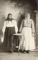 [Portrait of two Doukhobor women standing on either side of a table in an unknown location]