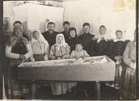 [Group portrait of a Doukhobor family standing next to an open casket in an unknown location]