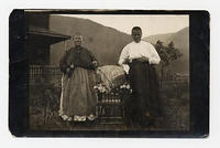 [Photographic postcard of two women beside a communal house, c. 1910s]