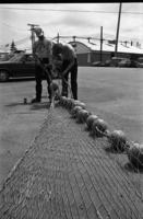 [Two men working on a fishing net]
